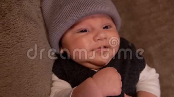 戴灰色帽子的小婴儿对着镜头微笑视频的预览图