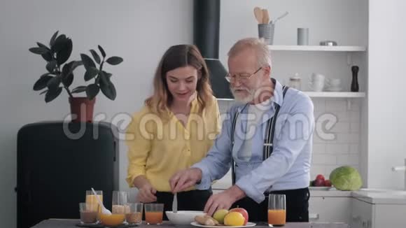 健康食品快乐的老人带着可爱的微笑留着胡子的女孩讨论早餐的食物喝果汁视频的预览图