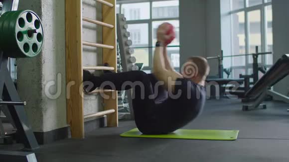 健身男在健身房用健身球做仰卧起坐视频的预览图