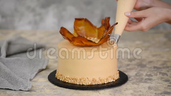 特写用焦糖奶油装饰蛋糕的女人的手视频的预览图