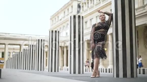 迷人的美女穿着性感的透明裙子和黑色内衣站在条纹柱子附近视频的预览图