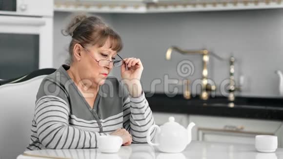 反思性中老年妇女在喝茶时戴眼镜思考问题视频的预览图