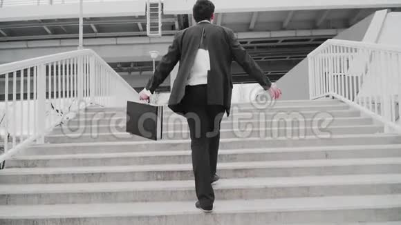 一个穿着破西装手拿公文包的家伙走上楼梯商人输家慢动作视频的预览图