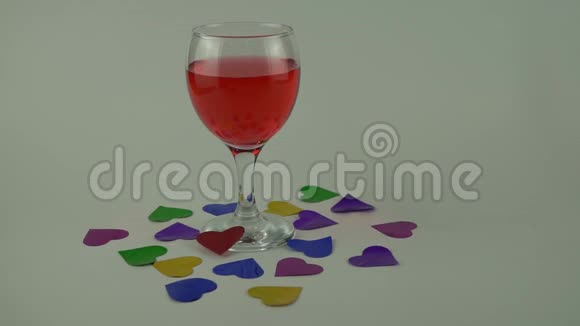 一杯白色背景的红酒心状的纸屑的散射视频的预览图