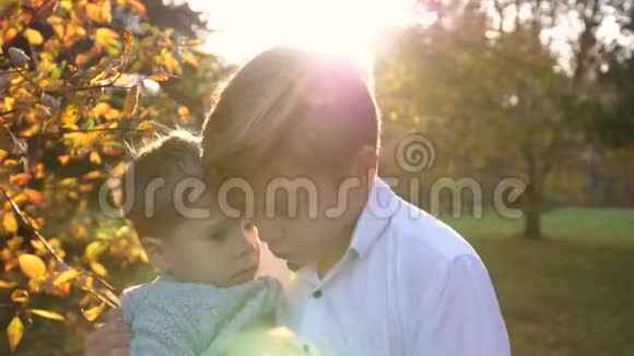一个少年和一个孩子玩把他抱在怀里太阳光线穿透孩子们欢笑和欢乐视频的预览图