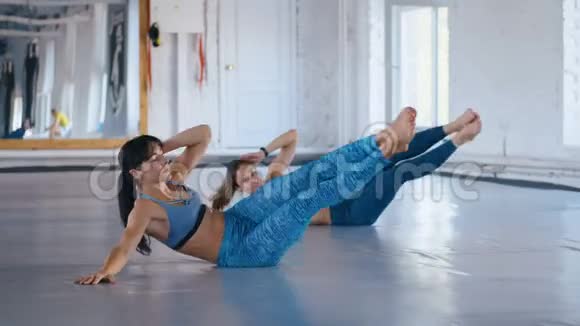 两名运动女性在健身馆的运动垫上做双腿举重女运动员通过改善肌肉视频的预览图