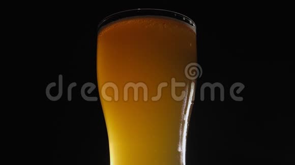一杯轻啤酒的特写在黑色背景上慢慢旋转视频的预览图