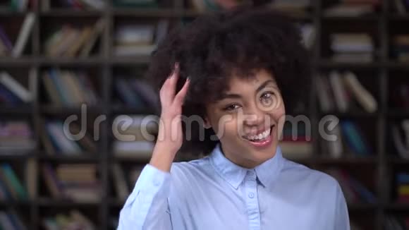 图书馆里的非洲年轻女子抚摸着卷发微笑视频的预览图