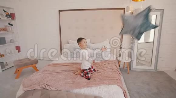 可爱的小男孩在卧室里抓一个星形枕头视频的预览图
