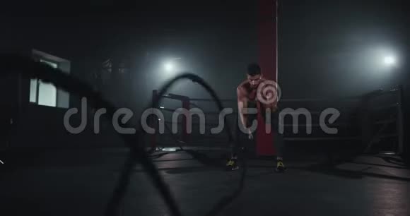 在一个现代的交叉健身班中健美男子用绳子做运动集中精力在前面工作视频的预览图