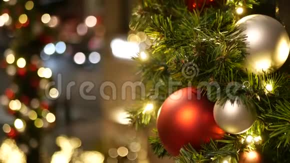 彩色装饰的户外圣诞树在模糊的闪闪发光的仙女背景上有明亮的红色球视频的预览图