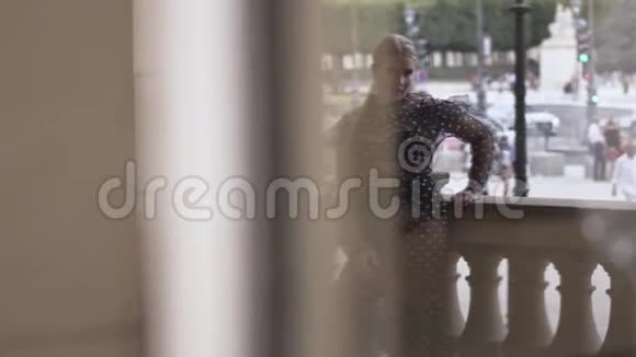 女人站在街上倒映在玻璃门上行动时尚性感的金发女孩穿着透明的视频的预览图