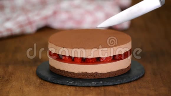 女人的手用覆盆子果冻切出美味的巧克力慕斯蛋糕视频的预览图