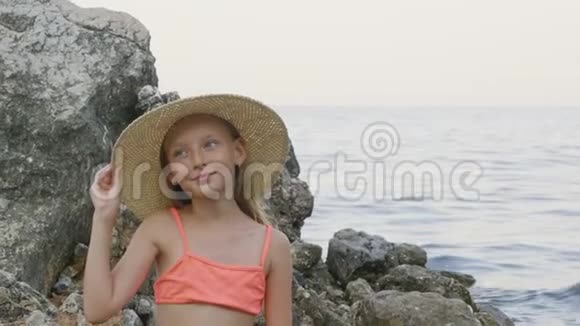 美丽的微笑少女戴着帽子在海边摆姿势视频的预览图