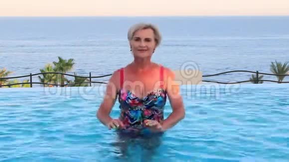 美丽的女人在沙滩上的游泳池里跳舞腰部深在水中视频的预览图