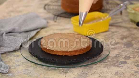在面包店做蛋糕的女孩面包师把奶油挤到蛋糕层上视频的预览图