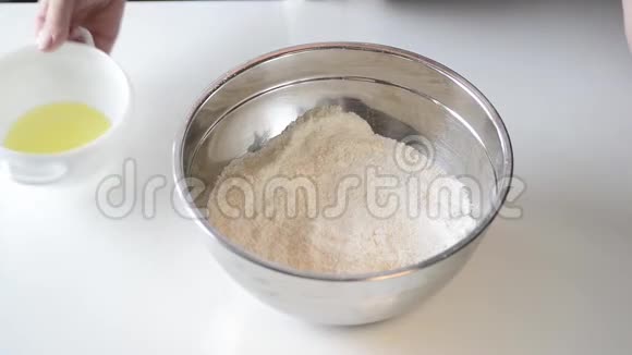 面包师用鸡蛋糖和面粉在白色桌子上的碗里准备面团女人混合配料做饼干视频的预览图