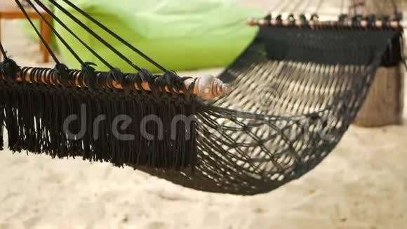 黑色吊床伸展在椰子手掌之间网眼老式的hipster吊床边缘延伸在沙地上视频的预览图