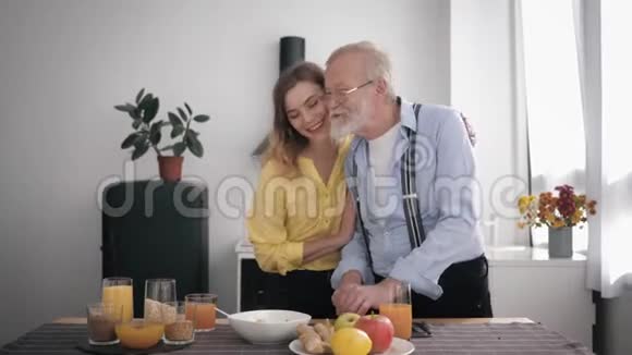 和她心爱的祖父一起带着眼镜在厨房里愉快地交谈和喝果汁视频的预览图