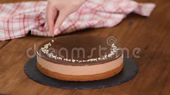 女人装饰和洒坚果顶部巧克力慕斯蛋糕视频的预览图