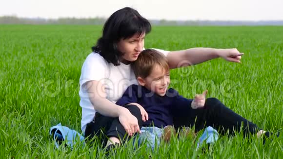 快乐的母亲花时间陪儿子放松坐在草地上一个女人和一个孩子用手指视频的预览图
