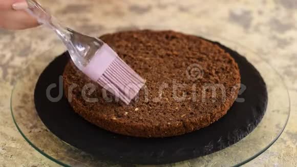 无法辨认的女性糖果手在厨房用硅粉刷用甜咖啡浸泡海绵蛋糕视频的预览图