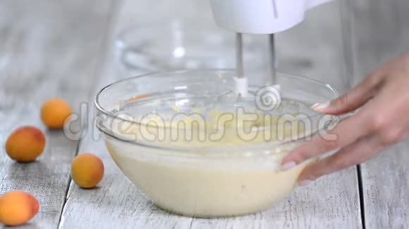 女孩用搅拌器把面团搅拌成一个杏糕视频的预览图
