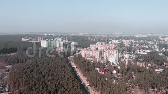 无人机飞过被森林包围的新建筑高层建筑的城市高层景观空中无人机拍摄的画面视频的预览图