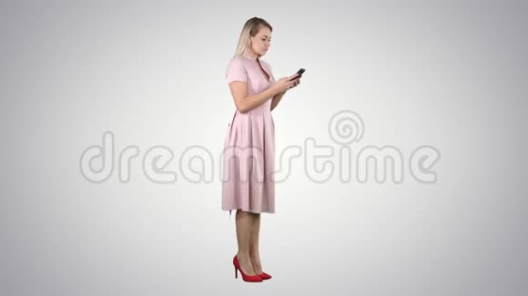 金发少女穿着粉红色短信在她的智能手机梯度背景视频的预览图