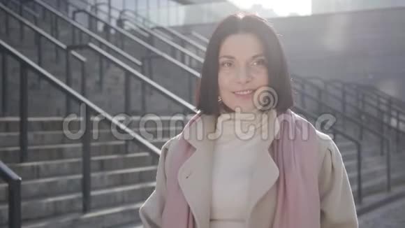 一位迷人的白种人女子站在城市街道上的阳光下微笑布鲁内特自信的商务小姐视频的预览图