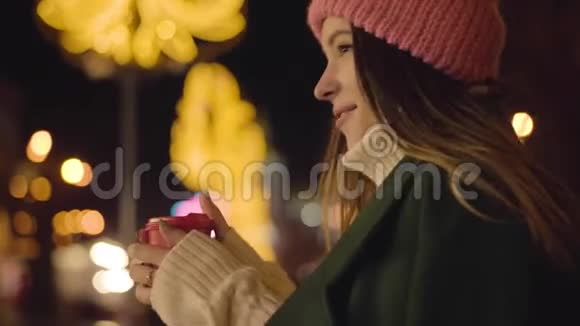 年轻的白种人女人站在室外喝咖啡杯环顾四周穿粉色帽子的迷人女孩视频的预览图