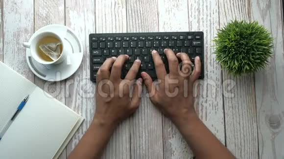 办公室桌上键盘上的人手打字的俯视图视频的预览图