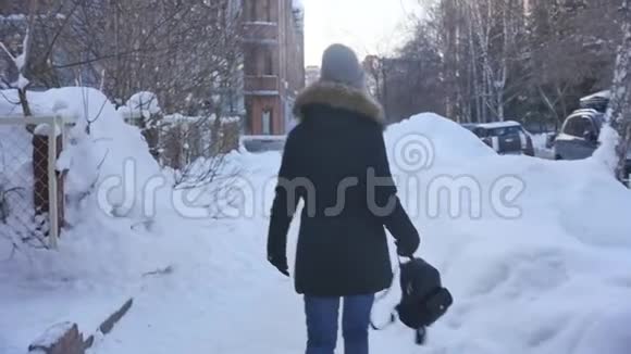 后景一位年轻美丽的女子穿着温暖的冬衣走在雪城里慢动作视频的预览图