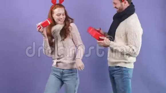 幸福的年轻夫妇穿着白色毛衣手里拿着圣诞礼物跳舞视频的预览图
