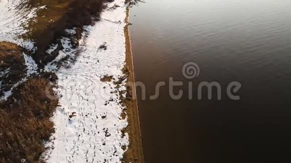 在温暖的冬日鸟瞰海岸线岸边的黄草和积雪全球变暖视频的预览图