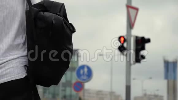 一个年轻人背着背包和一个包开着绿灯走着视频的预览图