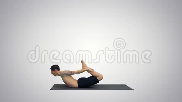 运动肌肉的年轻瑜伽男子做后弯运动达努拉萨纳弓姿势梯度背景视频的预览图