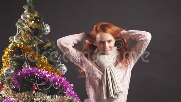 美丽的微笑女孩在工作室的圣诞树附近顺利地跳舞视频的预览图