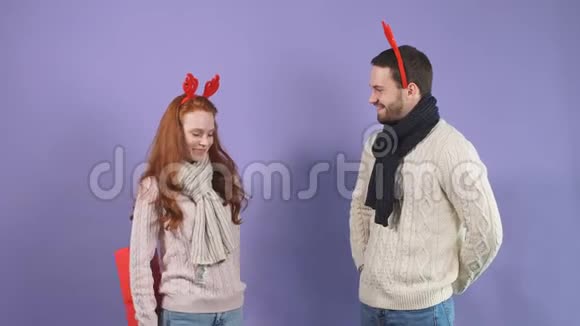 圣诞礼物快乐的一对情侣在淡紫色背景的工作室里送圣诞礼物视频的预览图