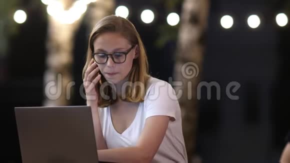 晚上在公园里ipster女孩通过手机随意交谈在上网本上做自由职业视频的预览图