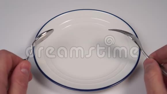 空的白色盘子在餐馆的桌子上有一个蓝色的边框在甜点叉子和勺子的手里视频的预览图