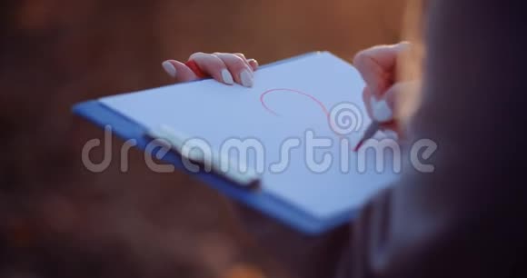 女人在剪贴板上画心脏符号视频的预览图
