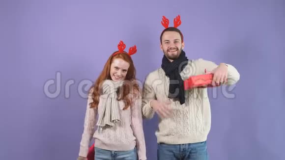 浪漫的幸福夫妇在紫罗兰色背景下摆着各种礼物红色的盒子视频的预览图