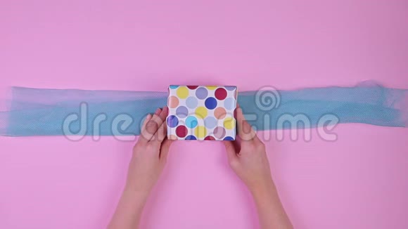 女孩用粉色背景包装礼物俯视图视频的预览图