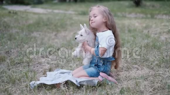 小金发女孩抱着西高地白梗小狗在公园视频的预览图