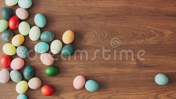 五颜六色的复活节彩蛋在木桌上滚动复活节节日装饰品复活节概念背景视频的预览图