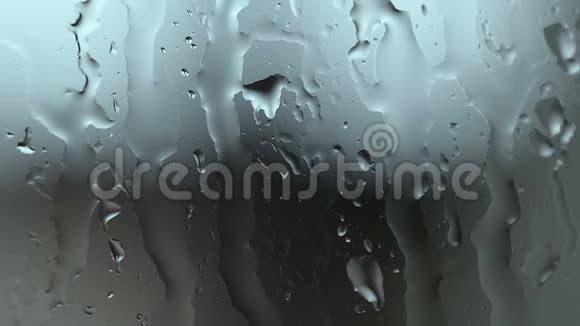 雨水滴在玻璃上模糊的蓝色背景抽象的液体运动视频的预览图
