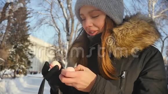 美丽的女人在冬天的城市公园里使用卫生的口红慢动作视频的预览图