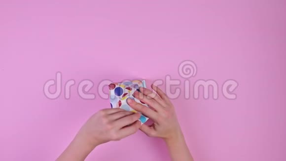 女孩用粉色背景包装礼物俯视图视频的预览图