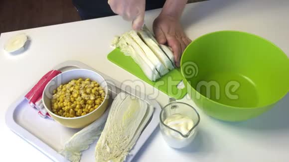 一个人做一份北京卷心菜沙拉在切割板上用刀子切卷心菜桌子旁边还有其他食材视频的预览图